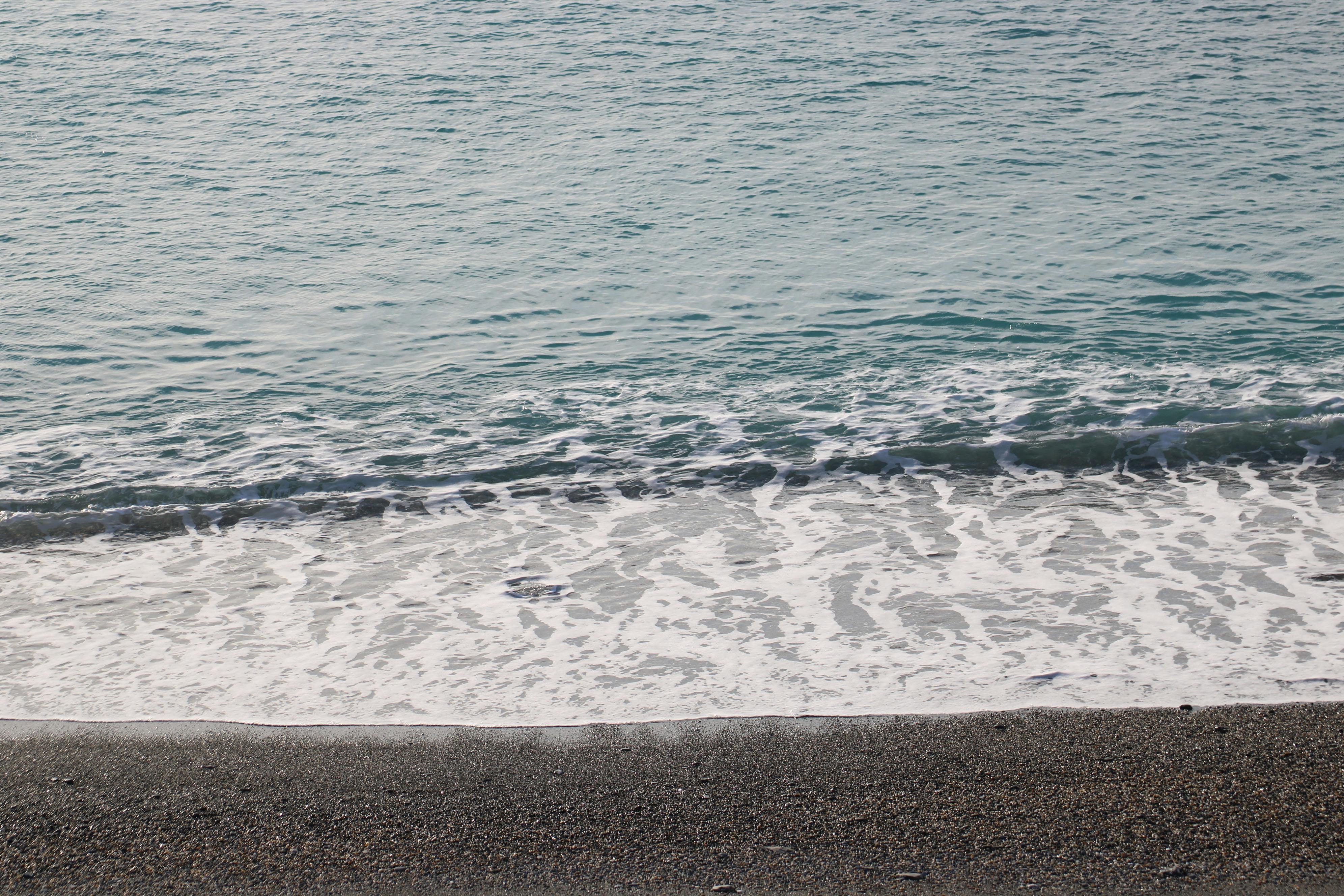 Gratis Scenario tranquillo con dolci onde su una tranquilla spiaggia di ciottoli, ideale per temi di relax. Foto a disposizione
