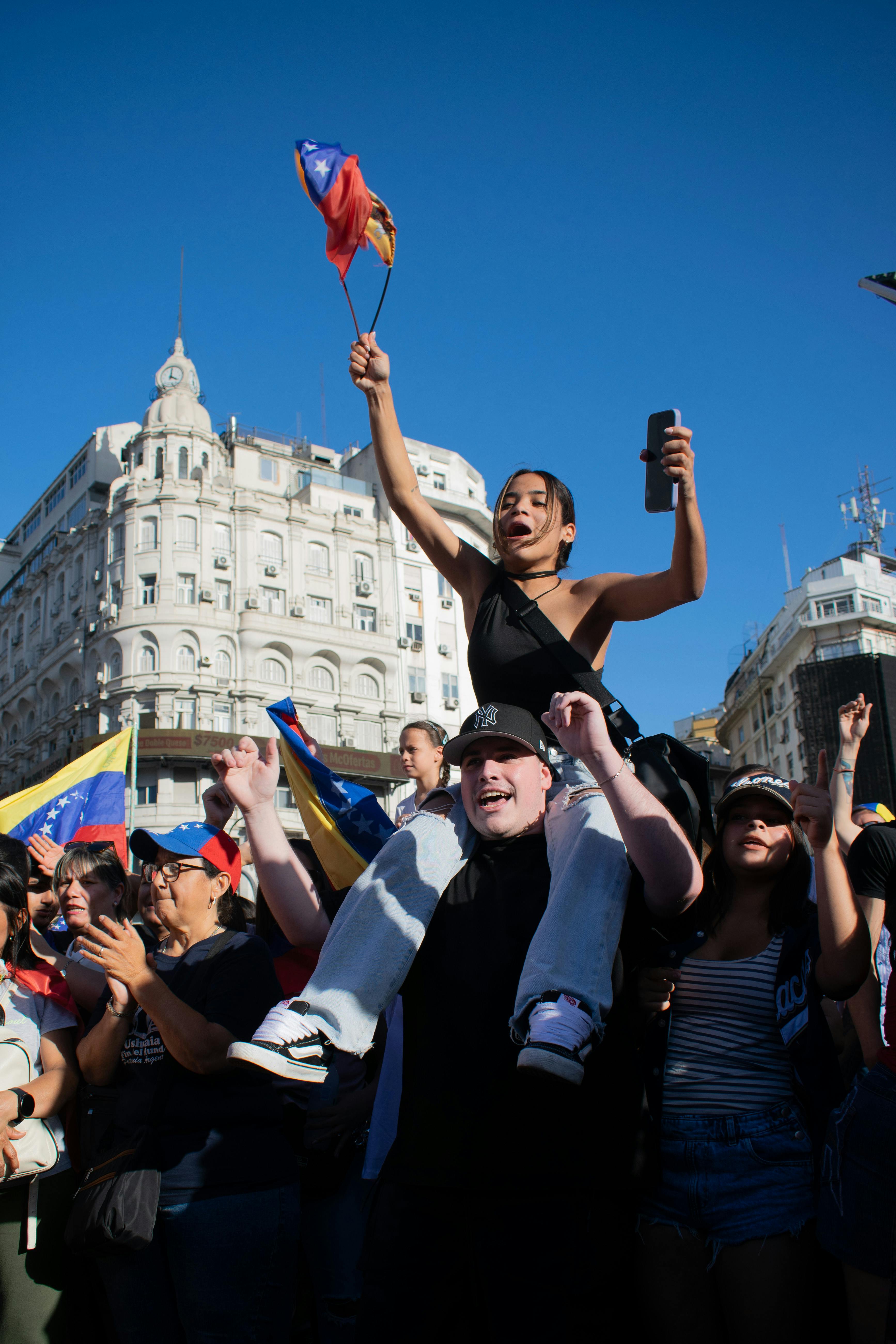 Gratis En livlig folkemengde i Venezuela protesterer med flagg under en klar blå himmel. Arkivbilde