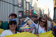 A vibrant street protest in Venezuela, showcasing joyous participants holding a political figure's portrait amid flags and smiles.