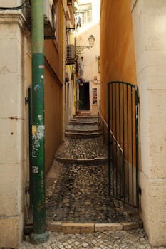 Explore the charm of a narrow cobblestone alleyway in historic Lisbon, Portugal.