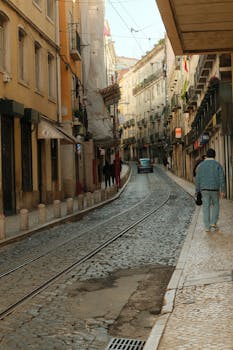 Quaint European city street with old buildings, cobblestone path, and tram tracks on a quiet day.