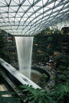 Experience the awe-inspiring indoor waterfall at Jewel Changi Airport in Singapore, surrounded by lush greenery.