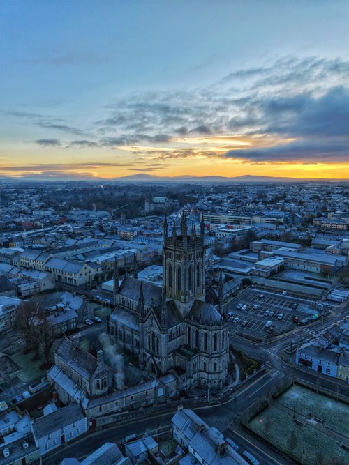 Free Stunning aerial view of Kilkenny Cathedral against a vibrant sunset sky. Stock Photo