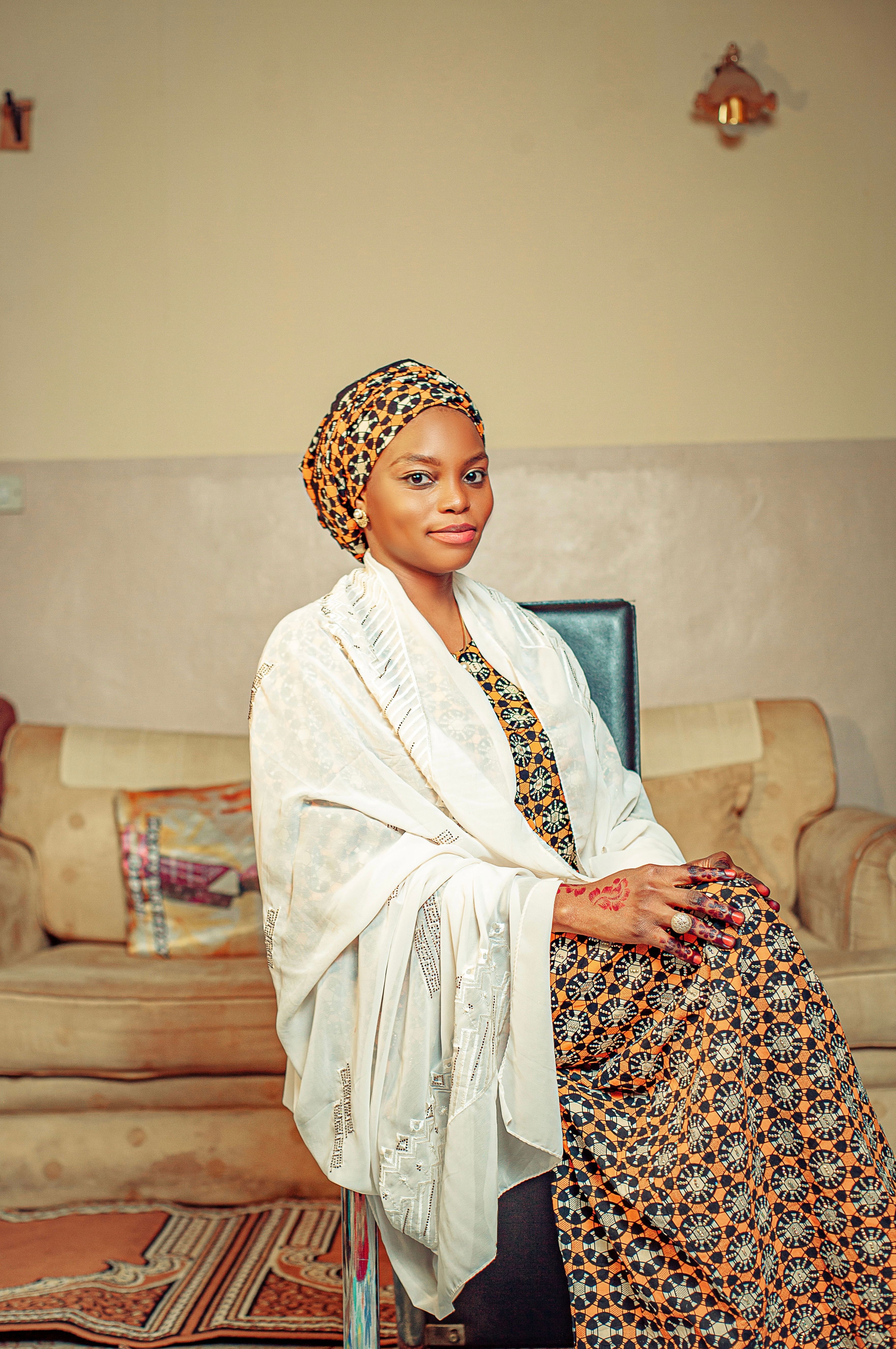 Graceful woman in traditional outfit seated indoors, exuding elegance.
