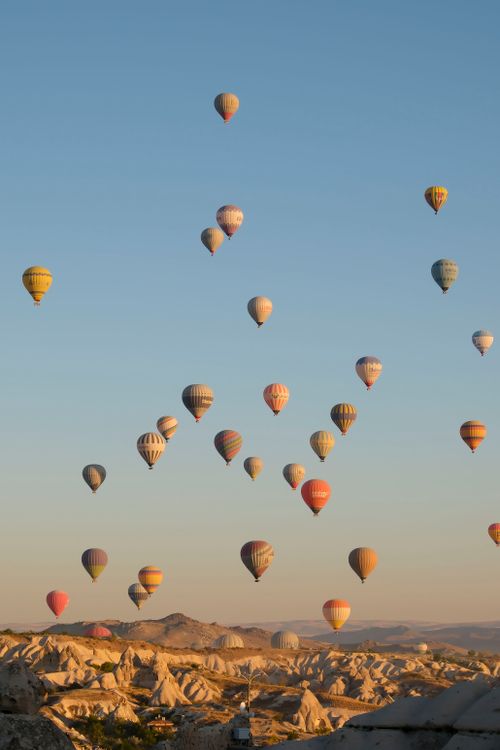 Free Hot air balloons soar over Cappadocia's unique landscape at sunrise, Türkiye. Stock Photo