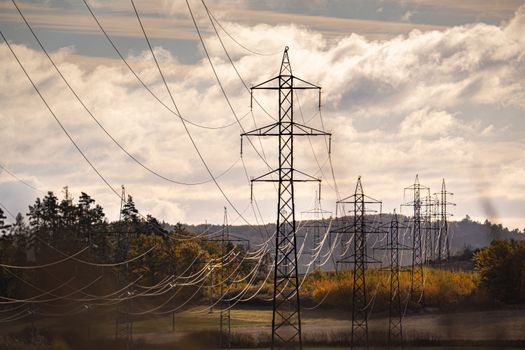Electric pylons stretch across a picturesque autumn landscape, under a dramatic sky.