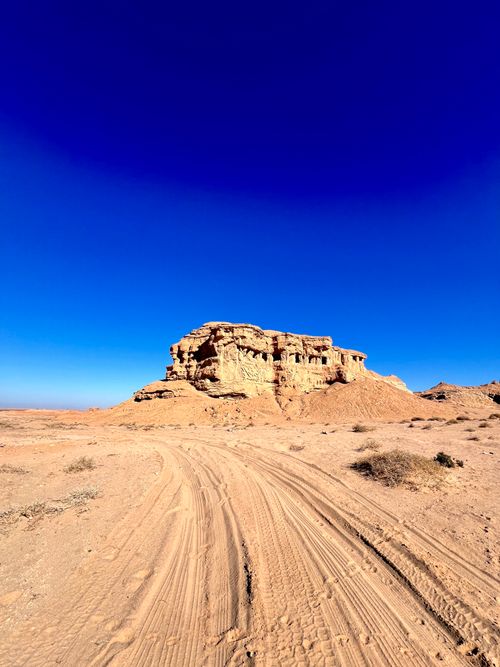 Free Stunning desert scene featuring a large rocky formation under a vivid blue sky. Stock Photo