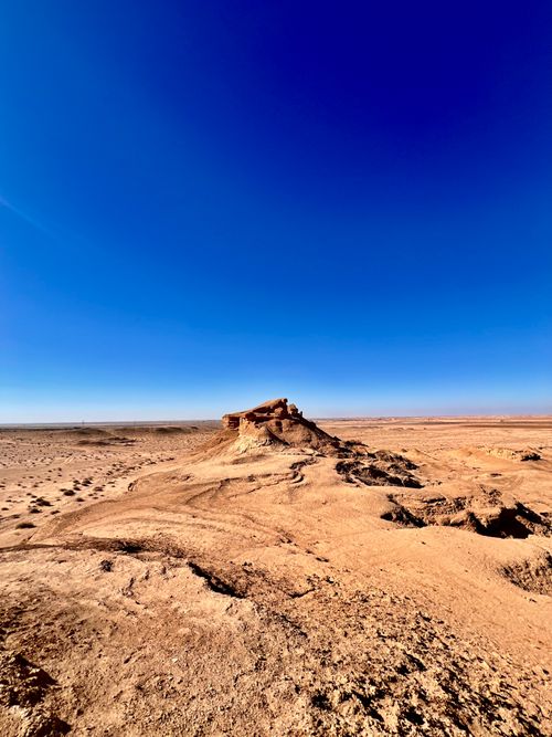 Free Expansive desert landscape with rock formations and clear blue sky. Stock Photo
