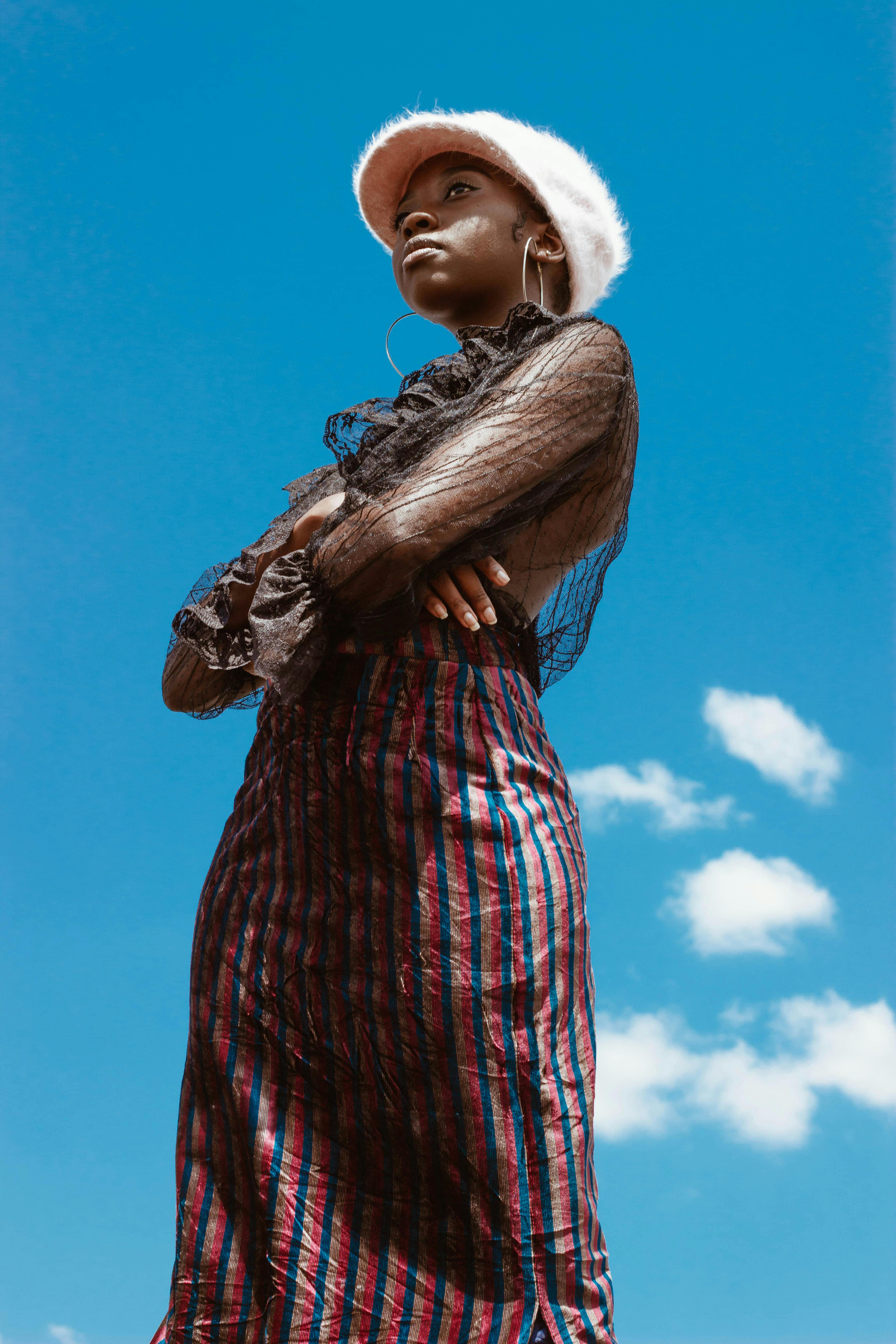Fashion-forward woman poses outdoors in vibrant attire under a clear blue sky.