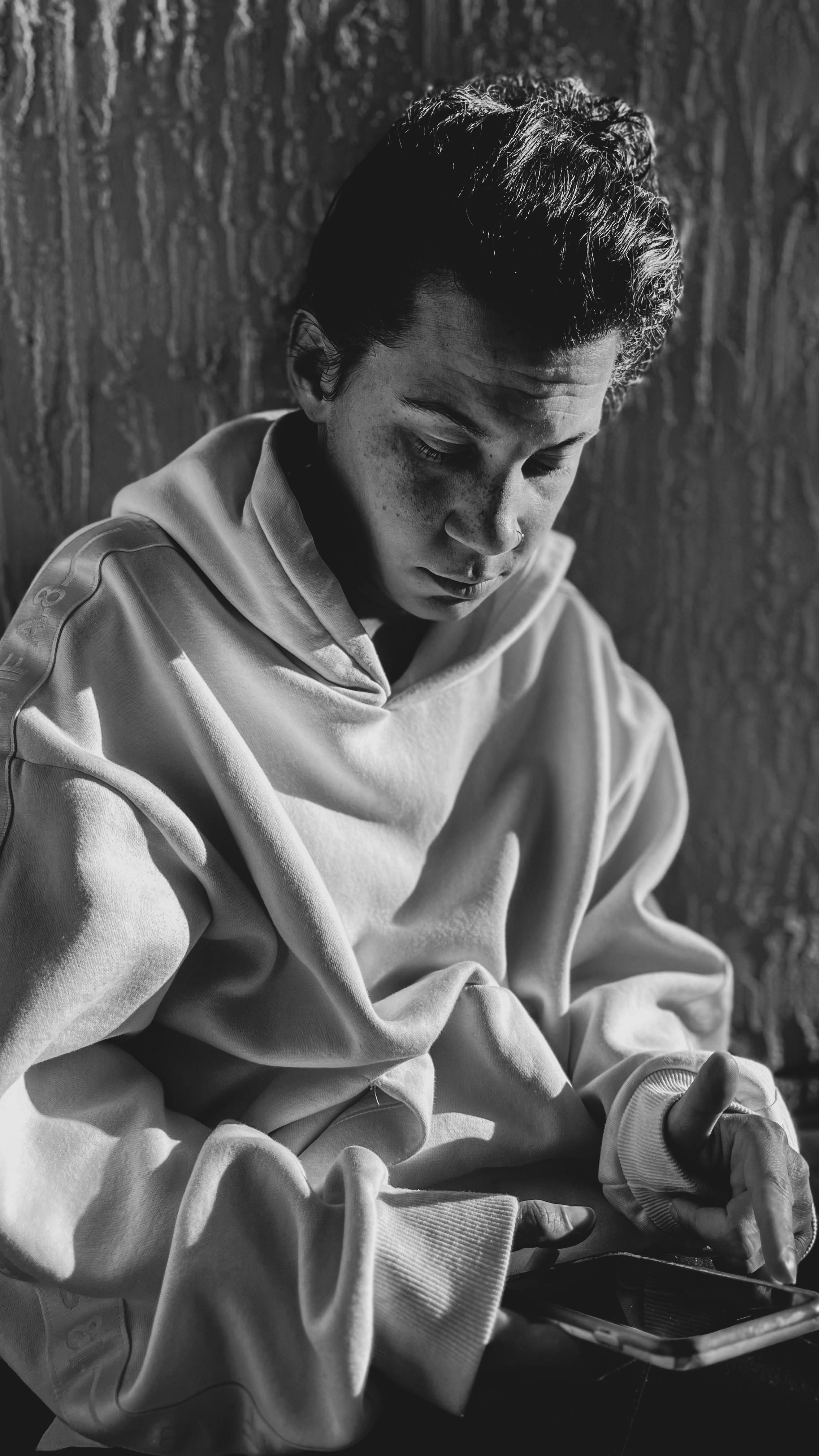 Moody black and white portrait of a young man using a smartphone. Emotional and introspective moment captured.