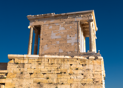 A close-up of an ancient temple's ruins on the Acropolis against a clear blue sky.