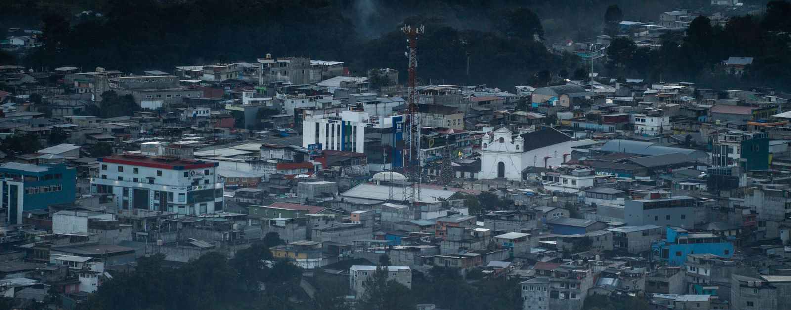 A stunning aerial view of Santa Cruz del Quiché, capturing its urban sprawl and surrounding landscape at dusk.