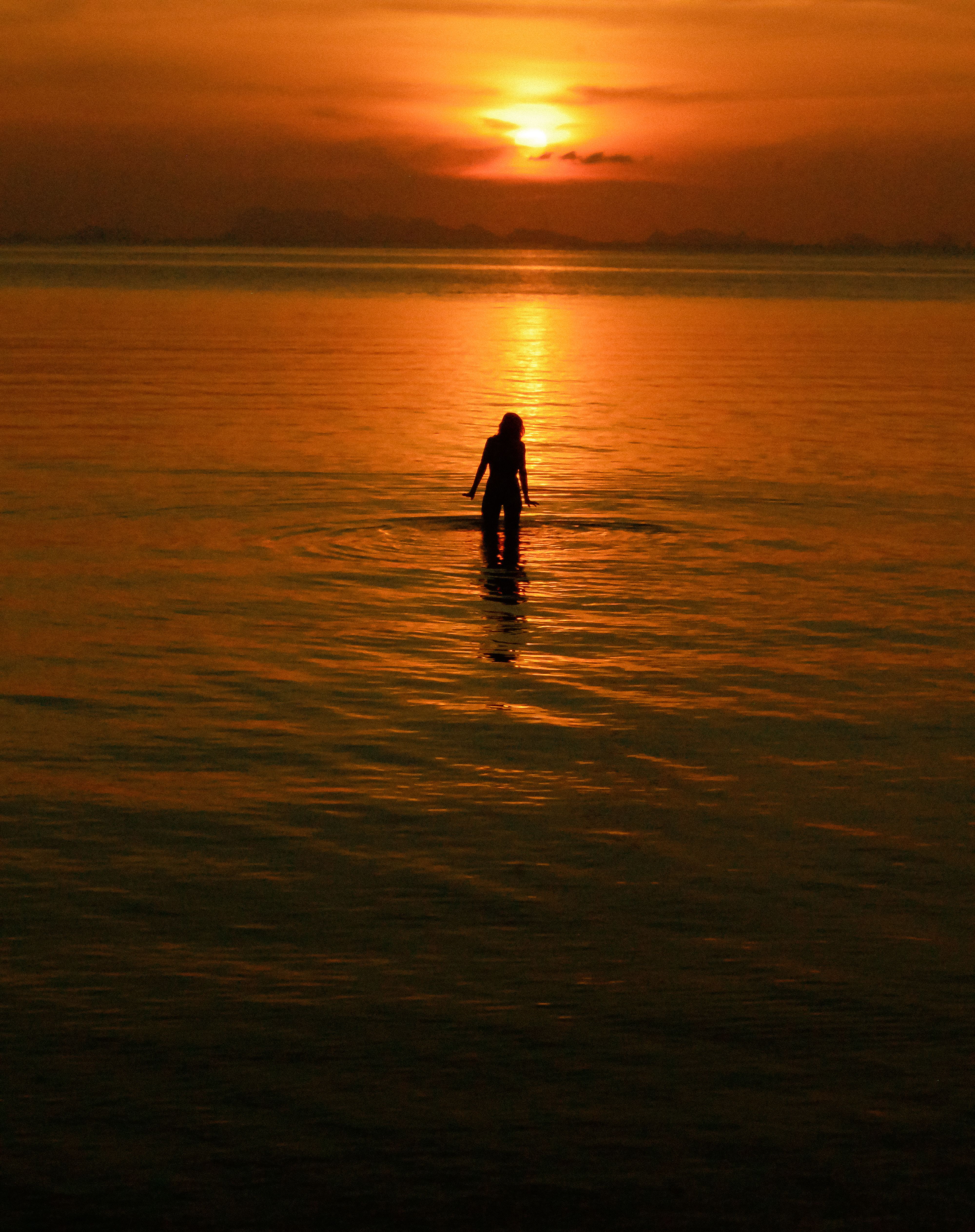 Silhouette of Person in Ocean at Orange Sunset · Free Stock Photo