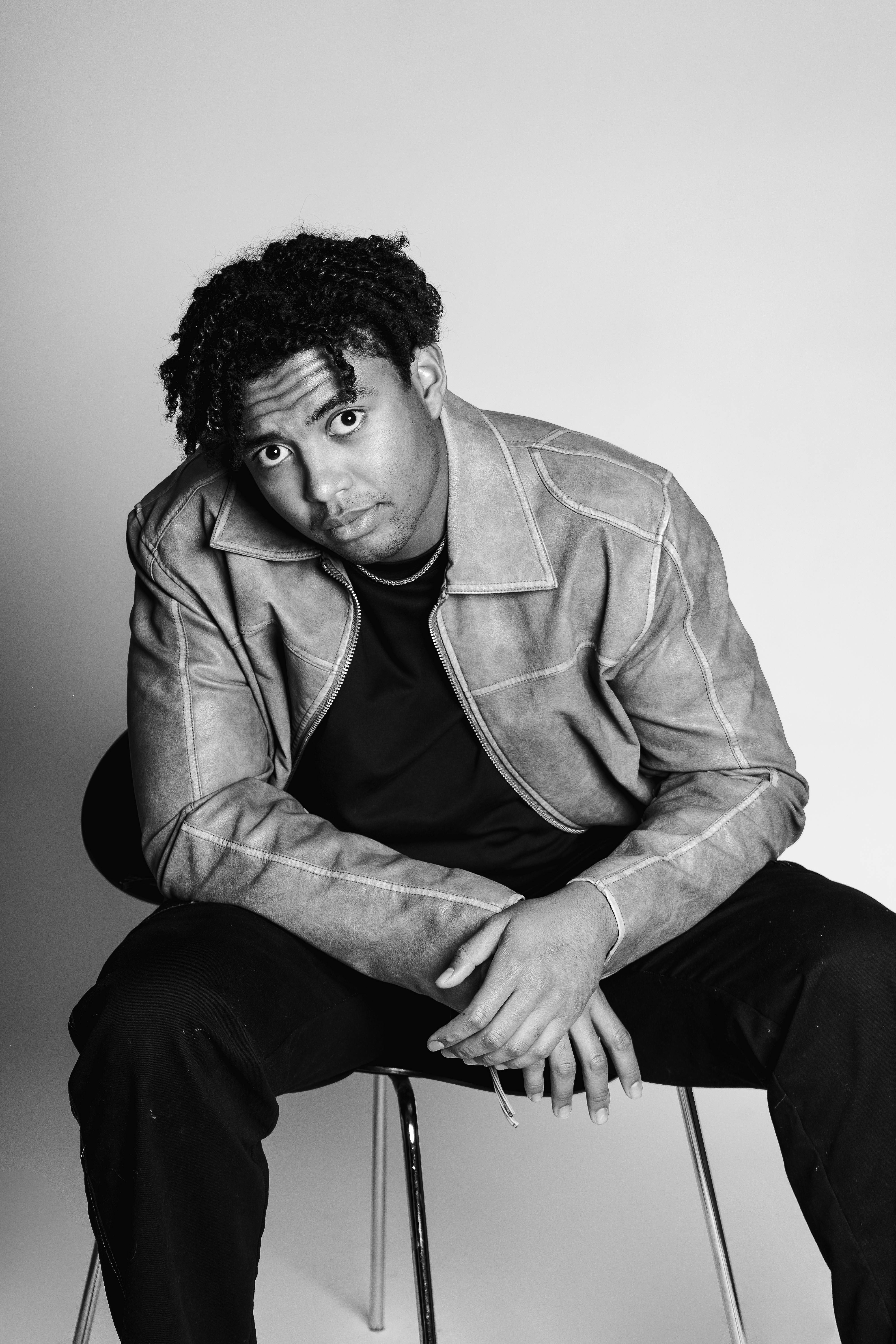 grátis Retrato artístico em preto e branco de um homem sentado, exibindo uma expressão pensativa. Foto profissional