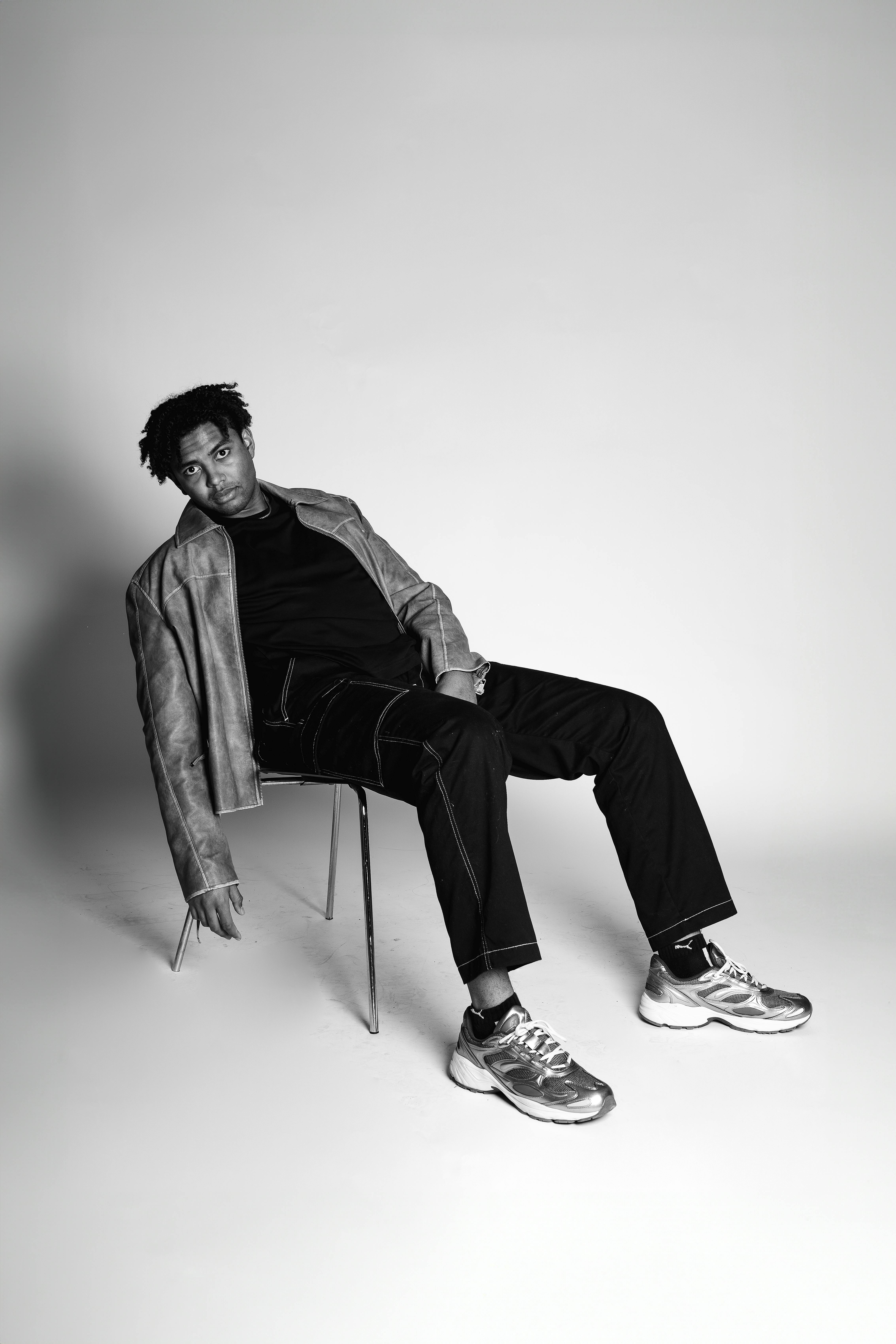 grátis Retrato monocromático de um adulto elegante sentado em um ambiente minimalista. Foto profissional