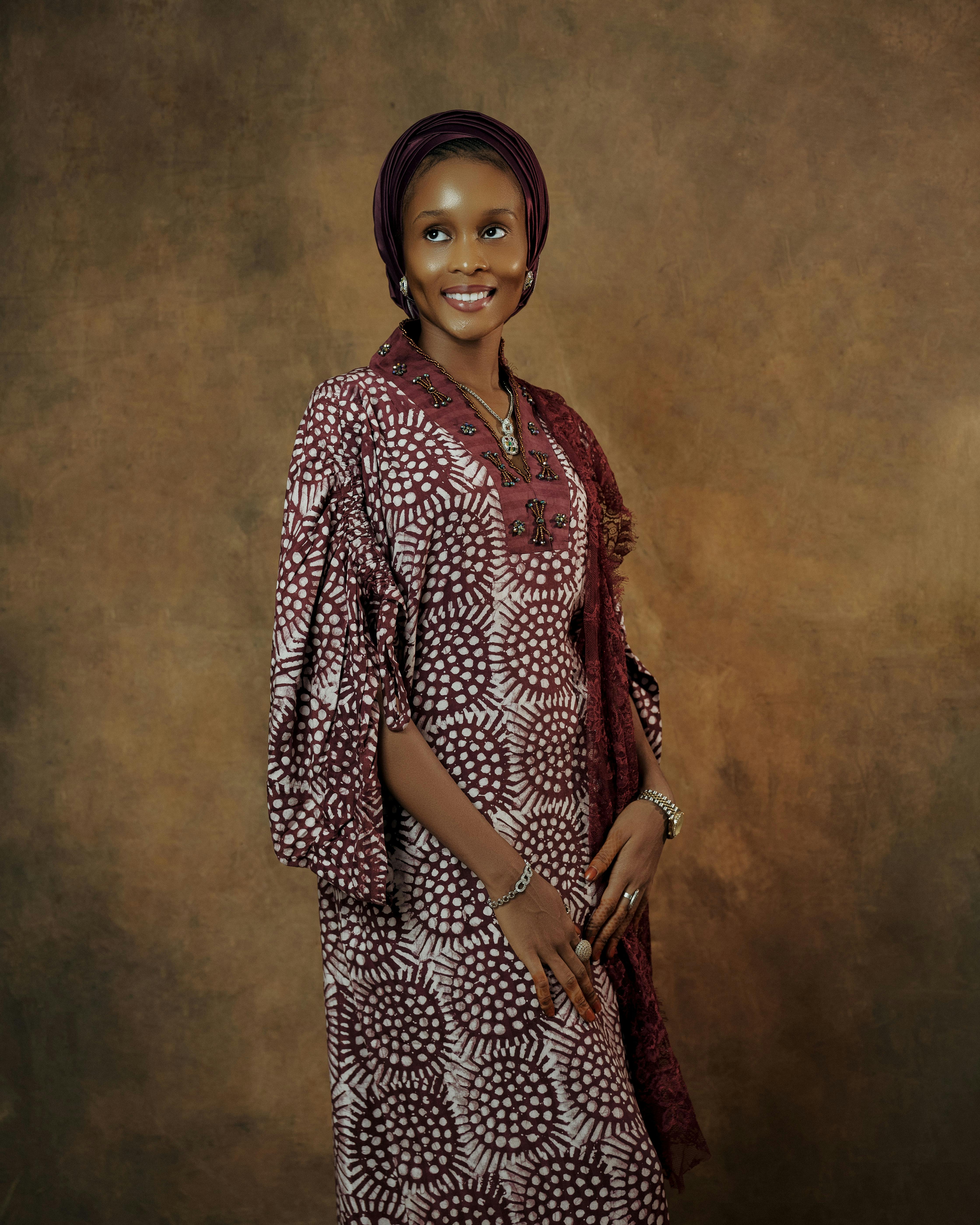 Gratis Mujer sonriente con vestido africano y pañuelo en la cabeza posando elegantemente en el interior. Foto de stock