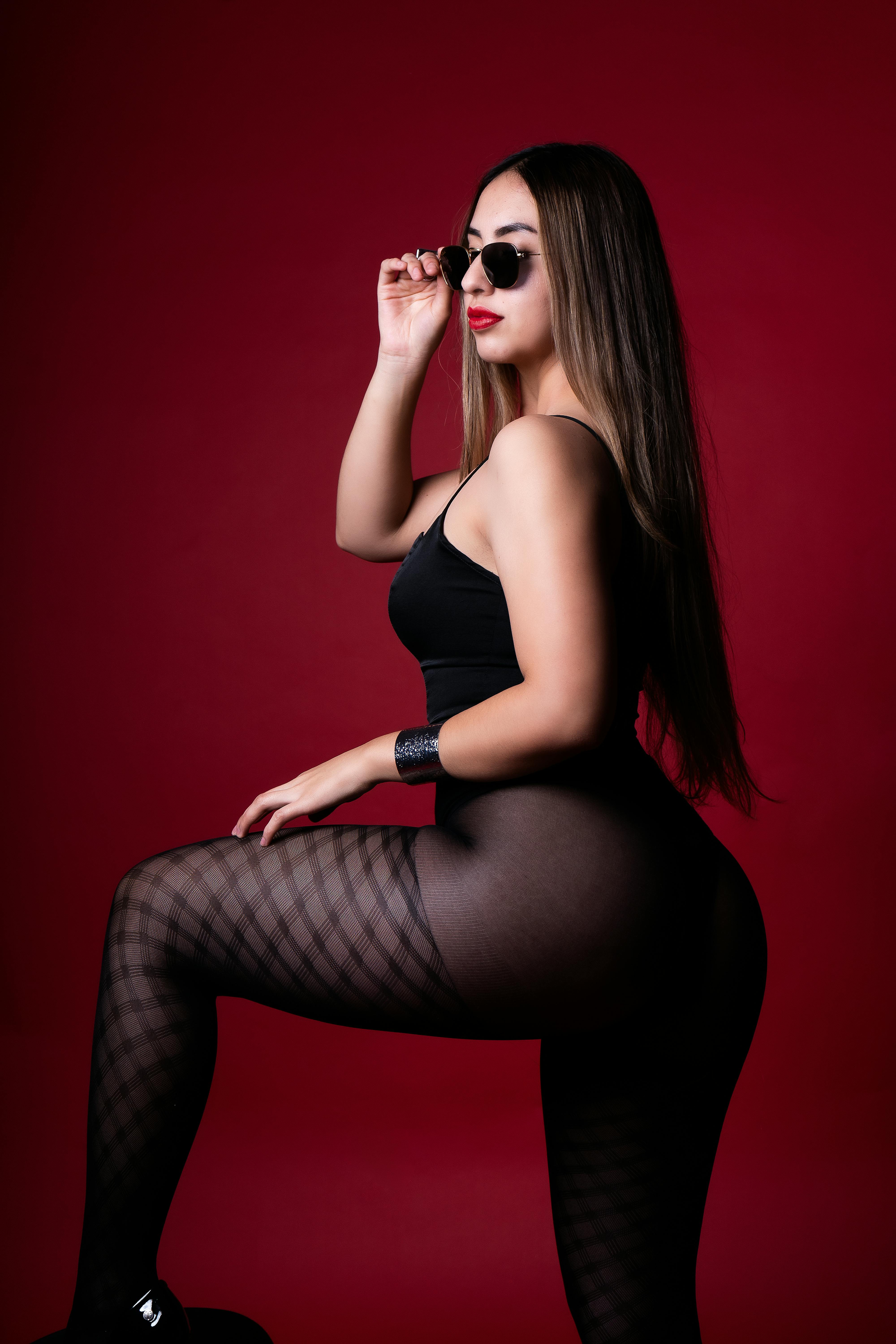 Portrait of a confident woman in stylish black attire against a red backdrop