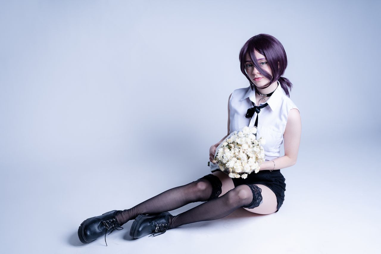 young adult in anime cosplay holding a bouquet sitting indoors