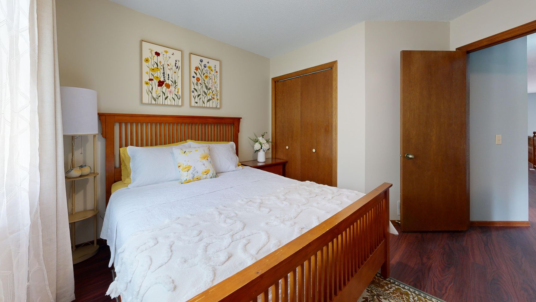 Traditional bedroom with several warm wood furniture pieces, pale bedding and a patterned rug