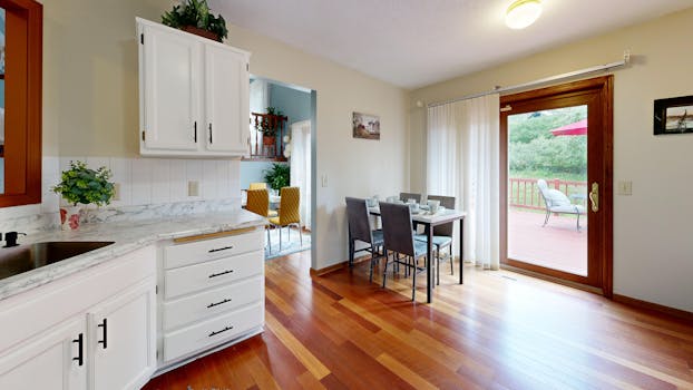 Spacious kitchen with dining area and deck access, featuring wooden floors and cabinets.