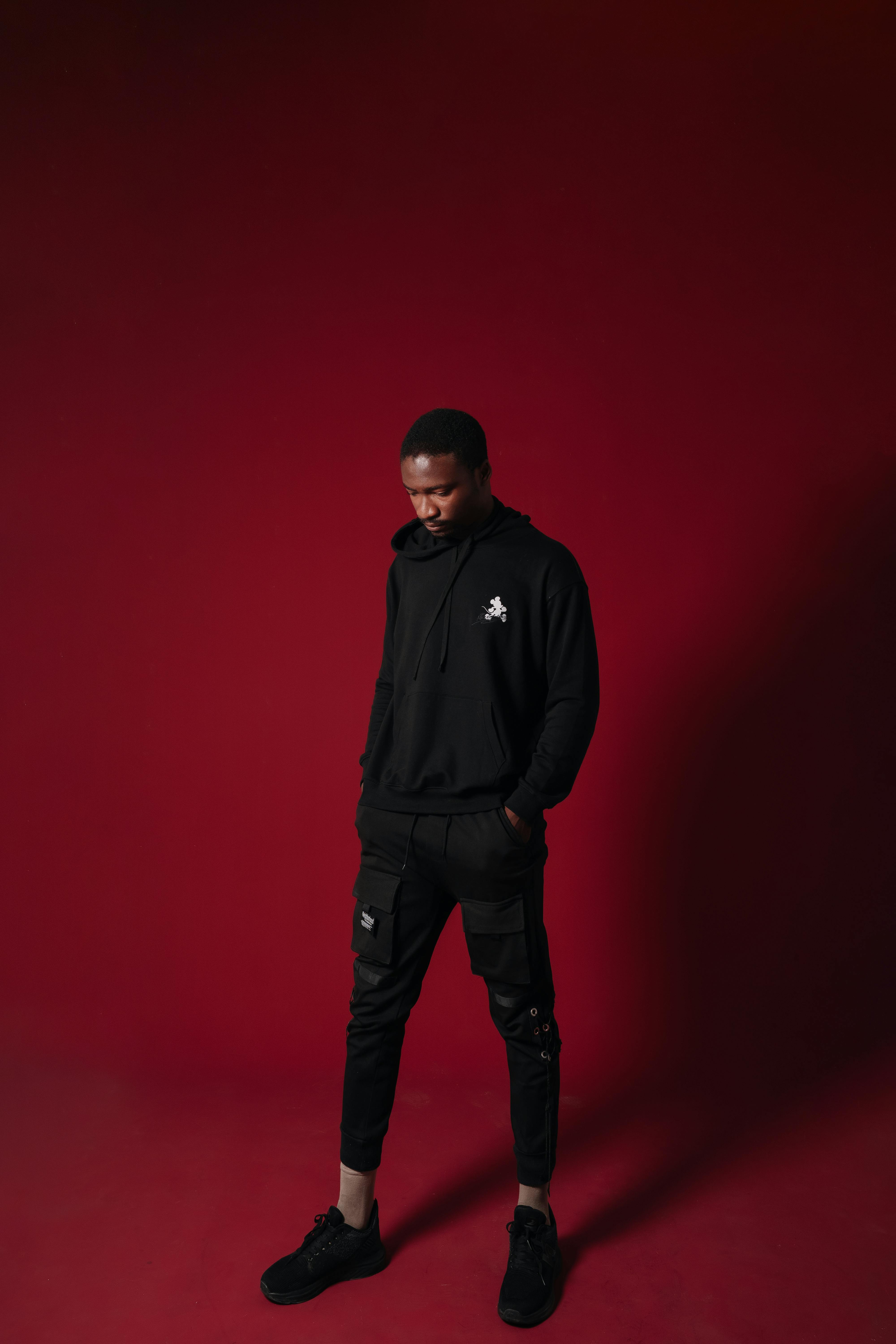 De franc Home amb un vestit negre modern sobre fons vermell fosc, que mostra un estil de moda modern. Foto d'estoc