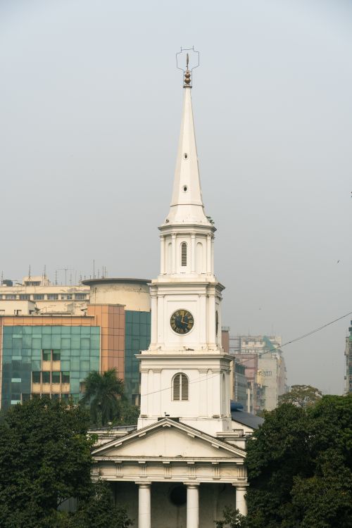 Free A prominent church tower rises amidst urban city buildings, showcasing classic architecture. Stock Photo