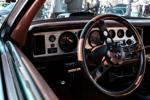 Interior view of a vintage car showcasing the classic steering wheel and dashboard design.