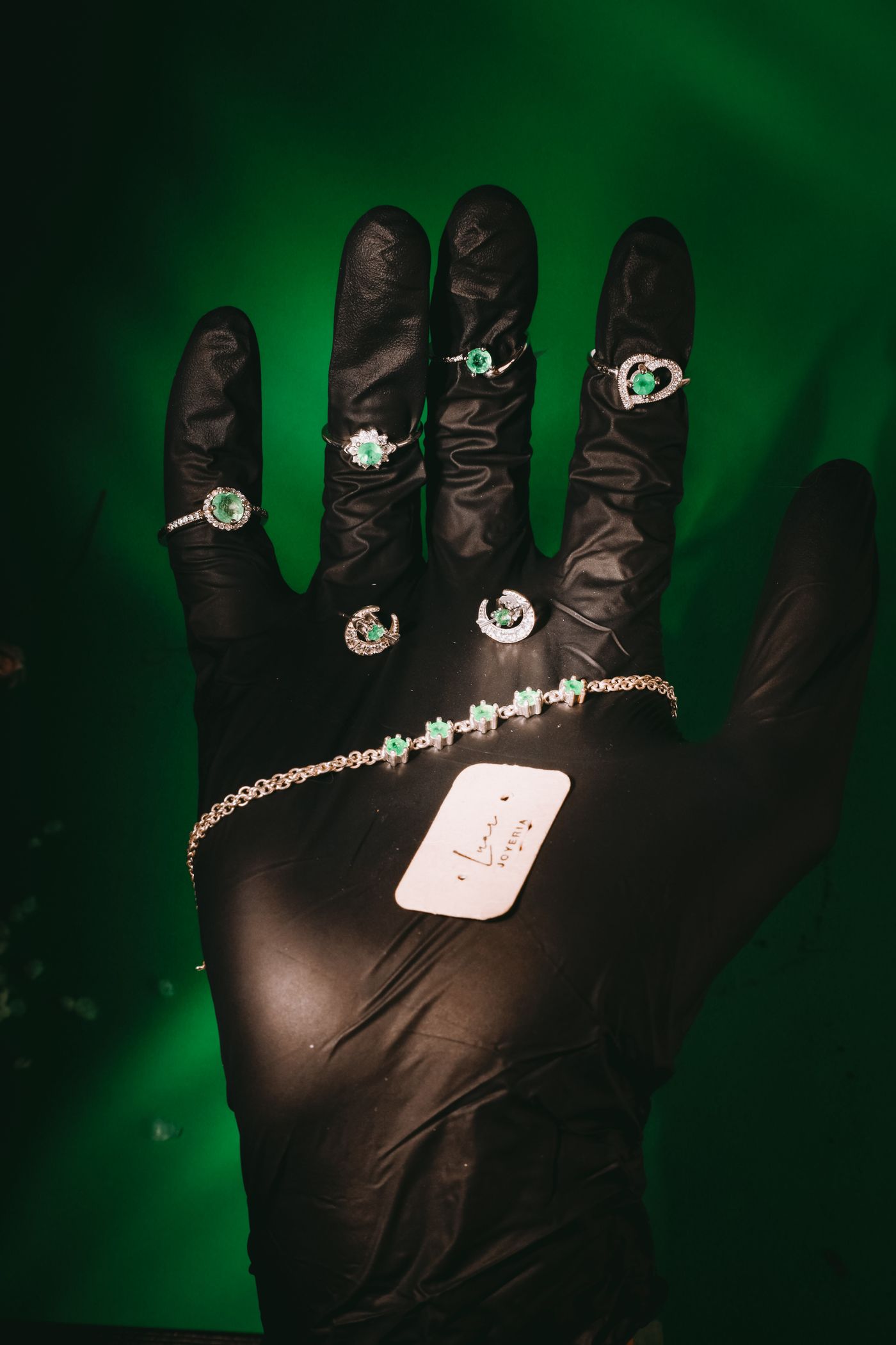 Finished emerald jewellery presented on a dark glove