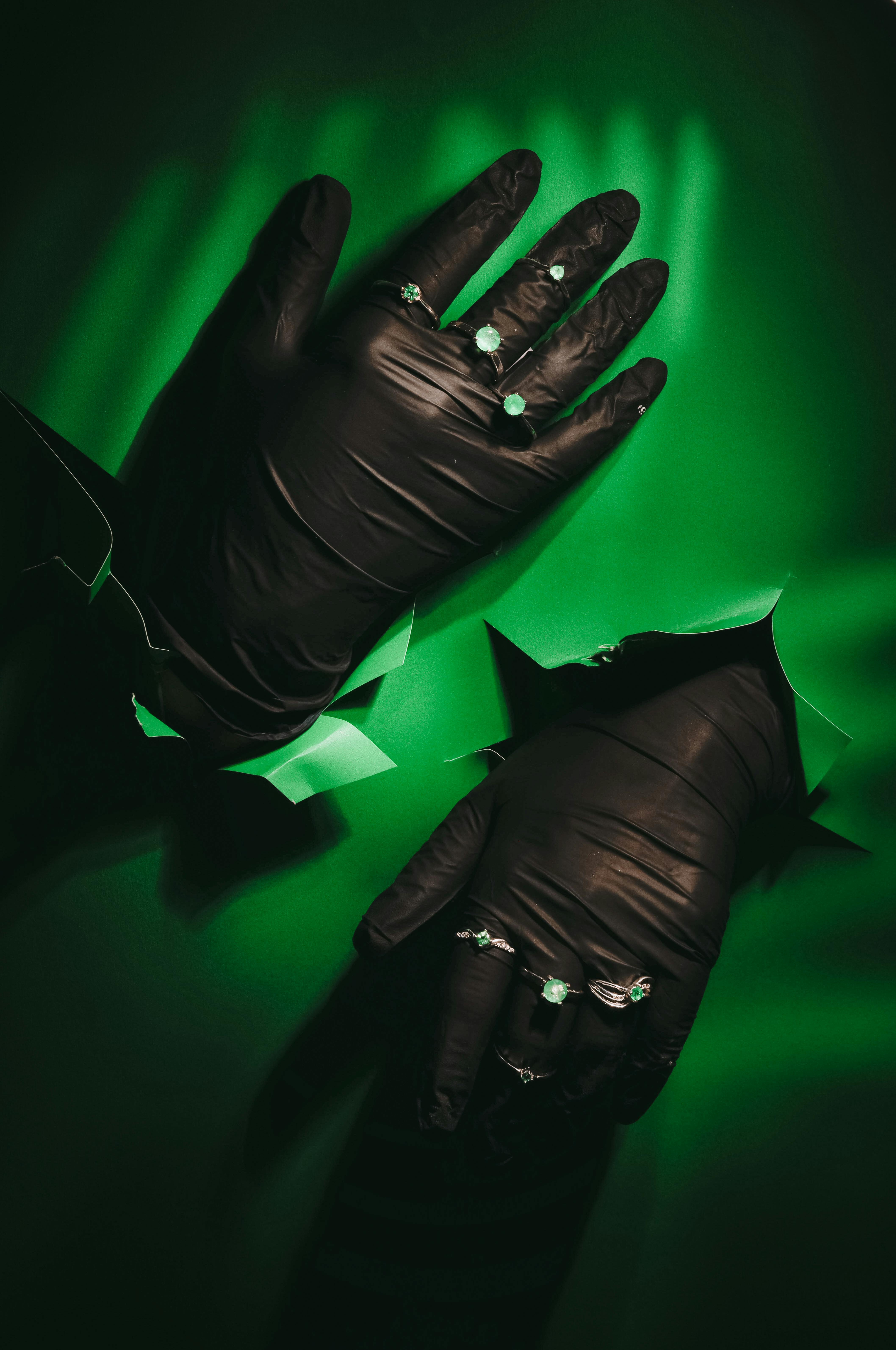 Gratis Svarte, behandskede hender utsmykket med smykker på en livlig grønn bakgrunn. Arkivbilde