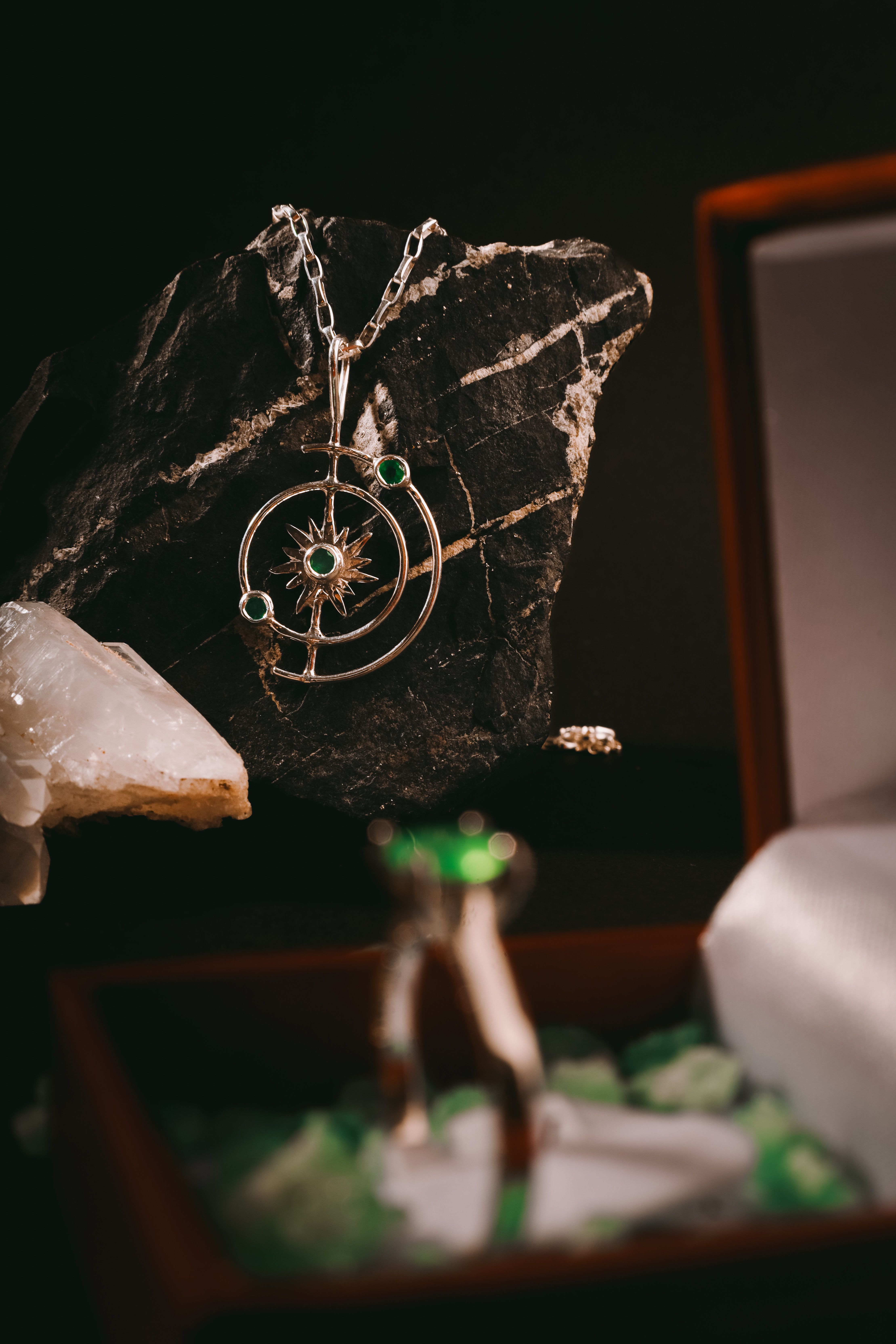 Close-up of a silver necklace with emeralds, elegantly displayed in a jewelry box.