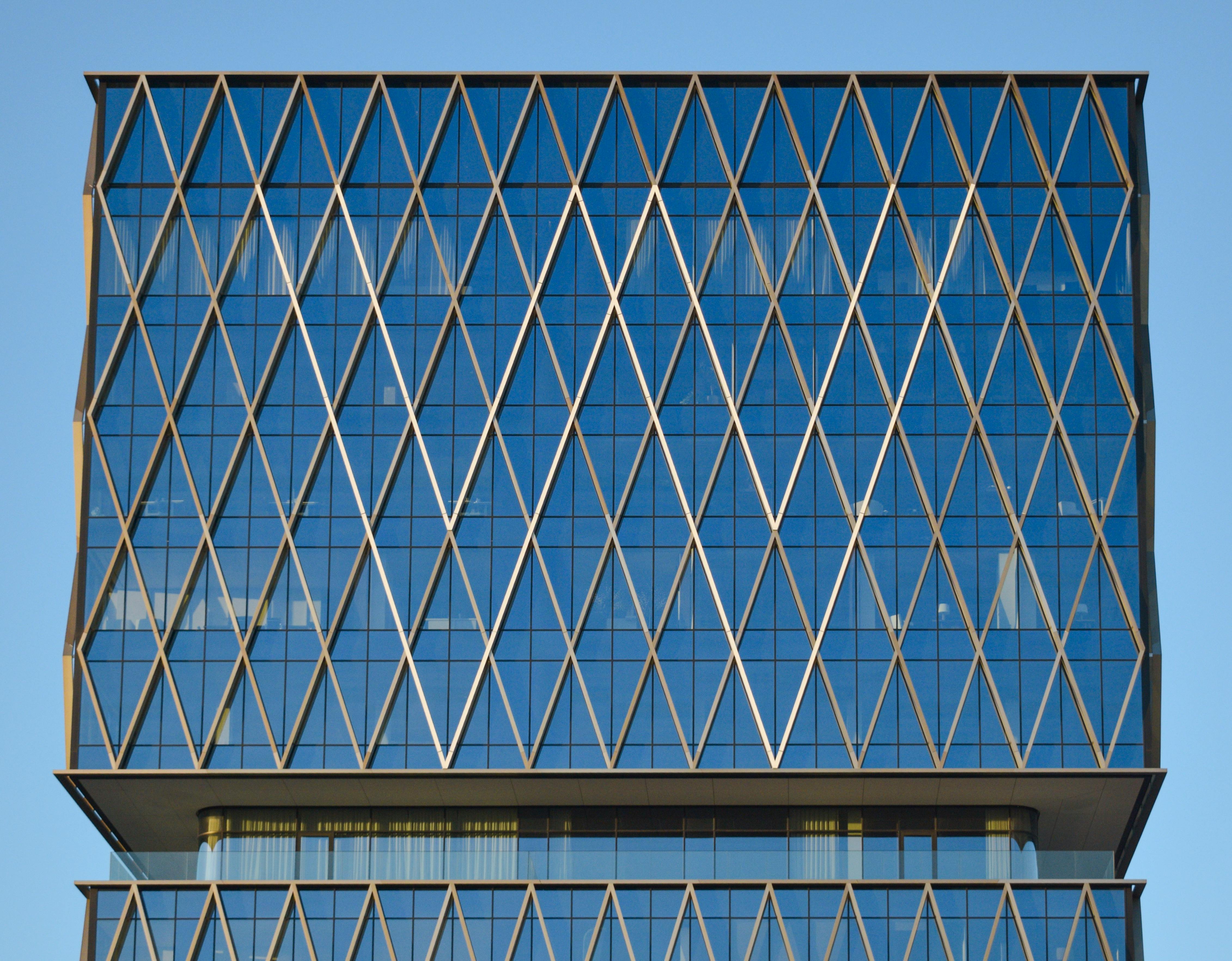 gratis Close-up van een moderne glazen wolkenkrabber met een gevel in geometrisch ruitpatroon. Stockfoto