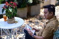 Man Relaxing Outdoors with a Book in Garden Setting