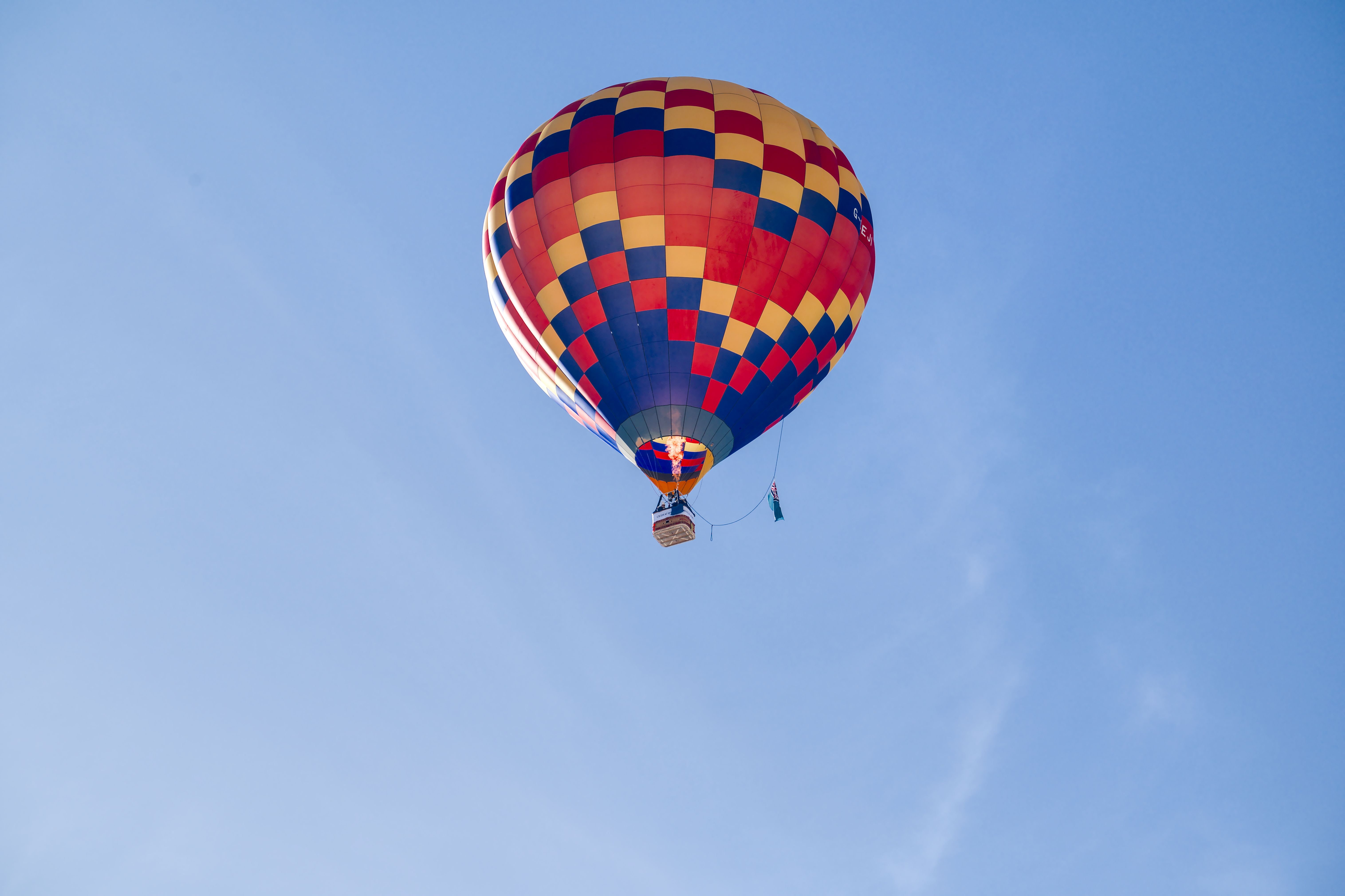 Colorful hot air balloon soaring high against a clear blue sky in Château-d'Oex, Switzerland.