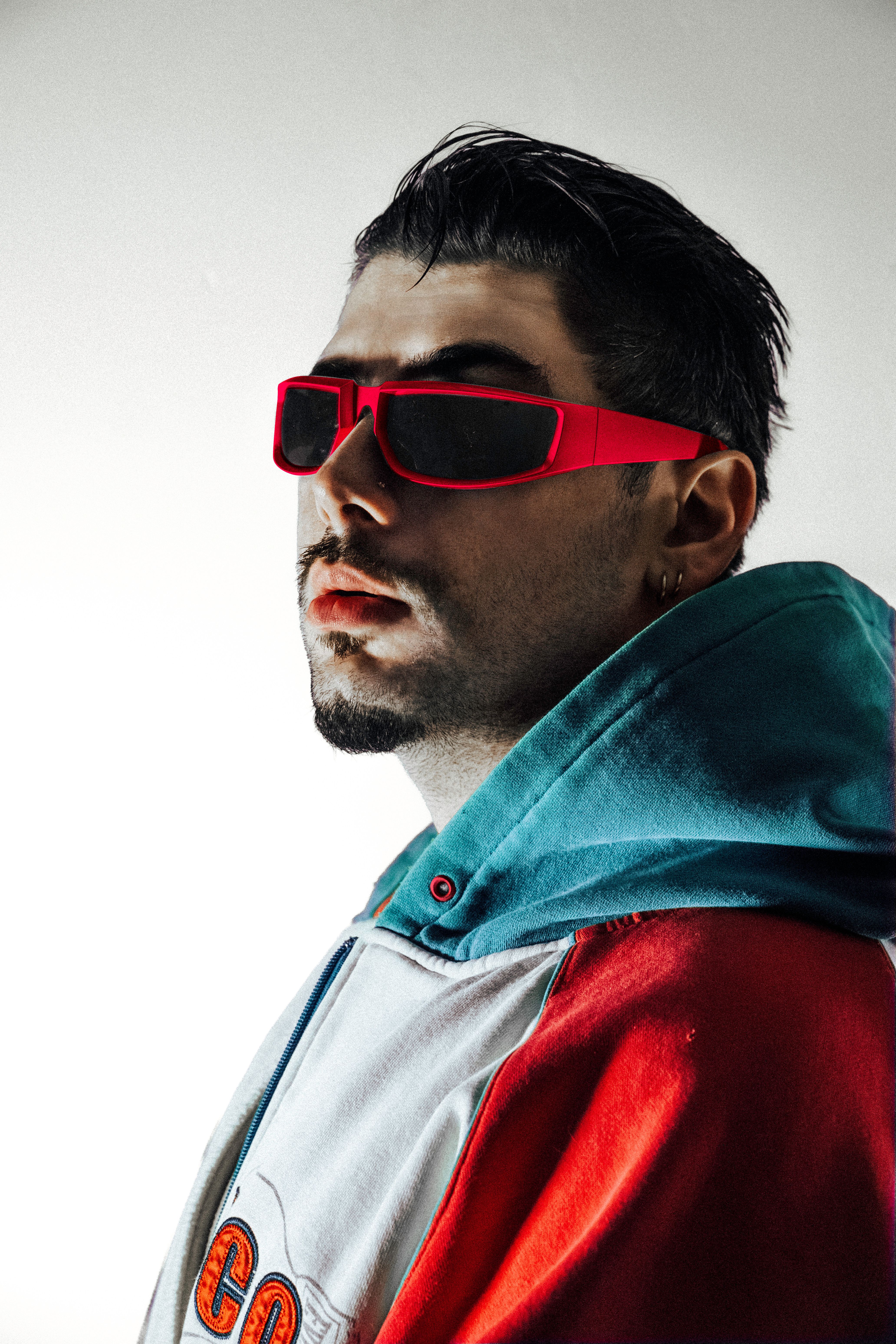 Portrait of a man wearing red sunglasses and a colorful hoodie in modern style.
