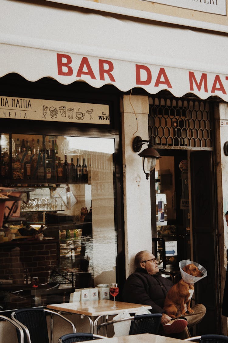 Old Man Sitting Near Entrance Of Cafe