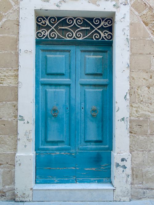 Free A vintage blue door with intricate metalwork set in a weathered stone wall, offering a rustic charm. Stock Photo