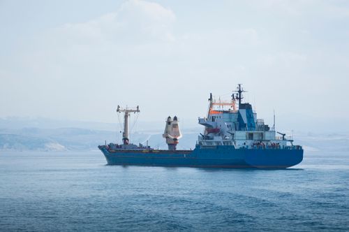 Free A large blue cargo container ship sails across the calm sea under a clear sky, symbolizing global trade. Stock Photo