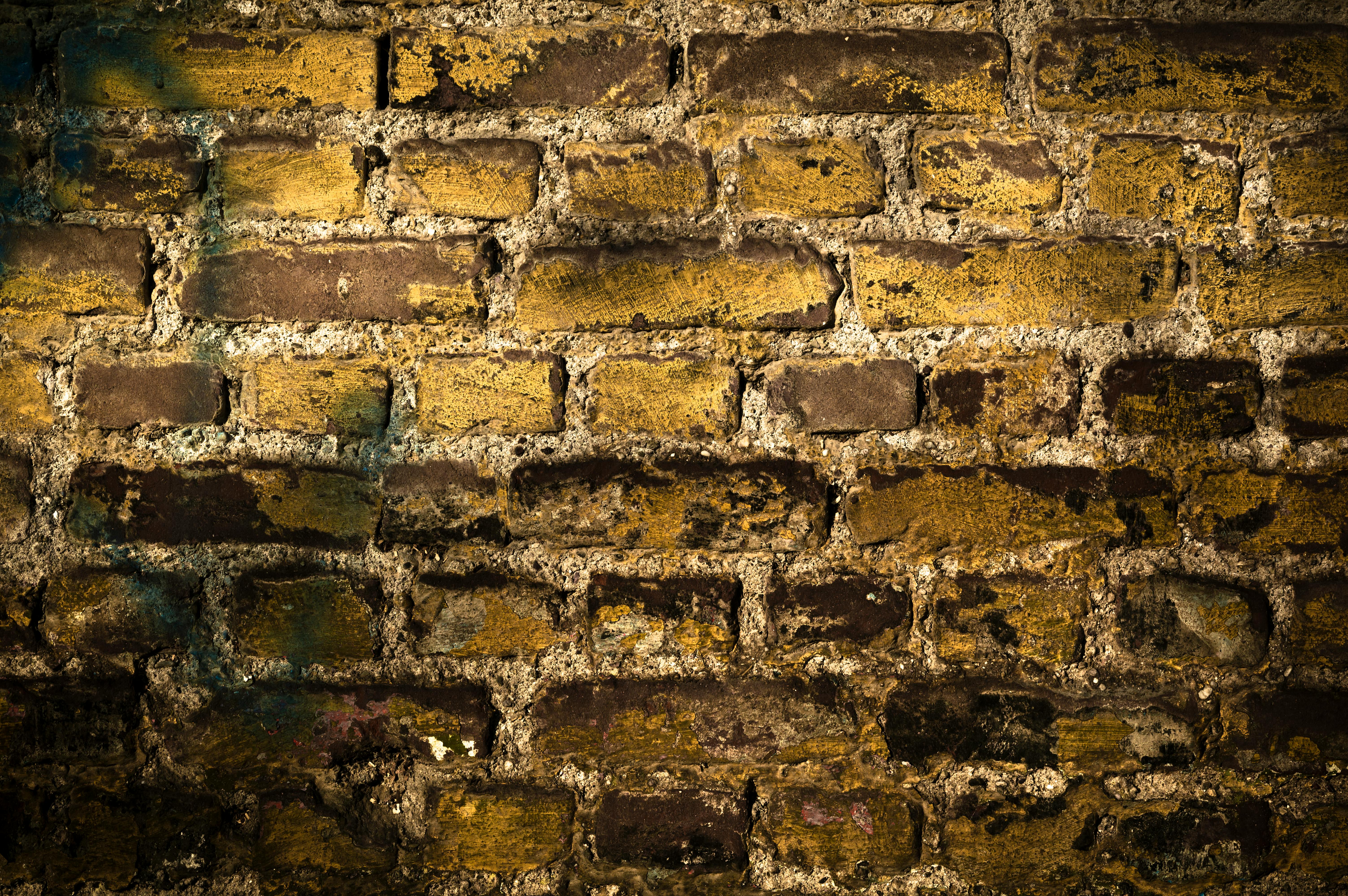 無料 暖色系のビネットを施した、古い質感のあるレンガの壁のクローズアップ。 写真素材