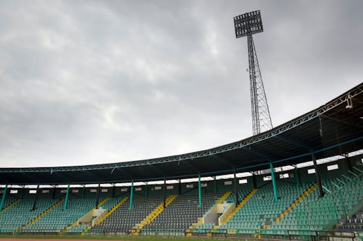 An empty soccer stadium with colorful seats under a cloudy sky, perfect for sports themes.