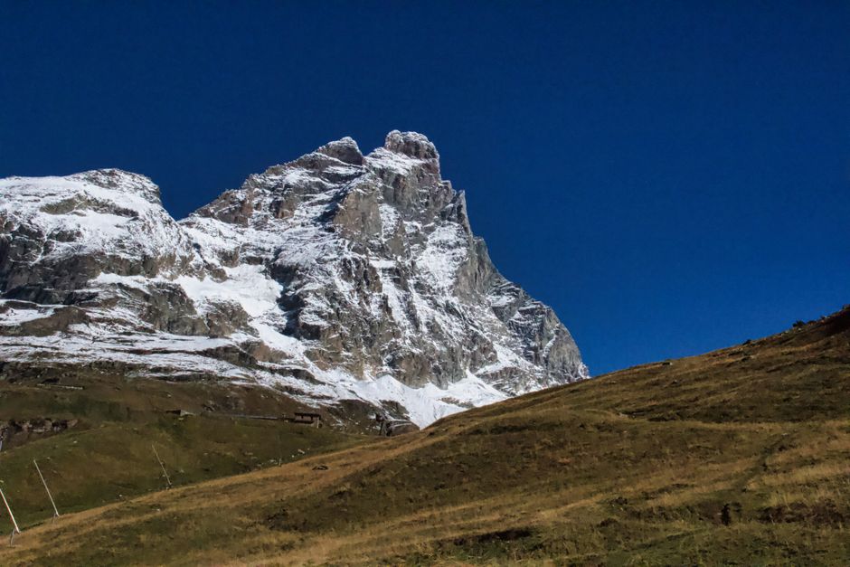 Majestic view of the snow-capped Matterhorn mountain in Breuil-Cervinia, Italy, under a clear blue sky.