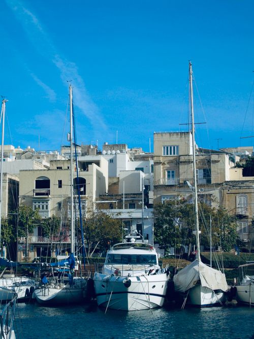 Free Boats docked in a scenic Mediterranean marina with historic buildings in the background. Stock Photo