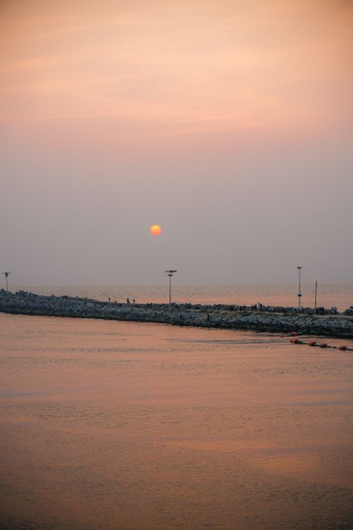 Free A beautiful sunset casts a warm glow over the calm ocean horizon. Stock Photo