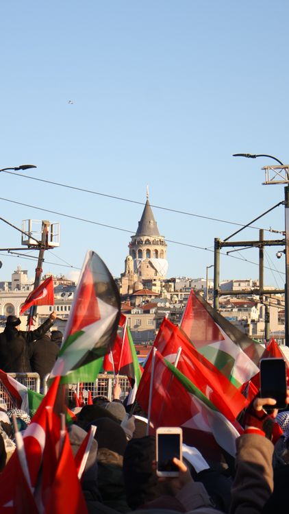 Free A lively crowd with flags gathers beneath the iconic Galata Tower in Istanbul. Stock Photo