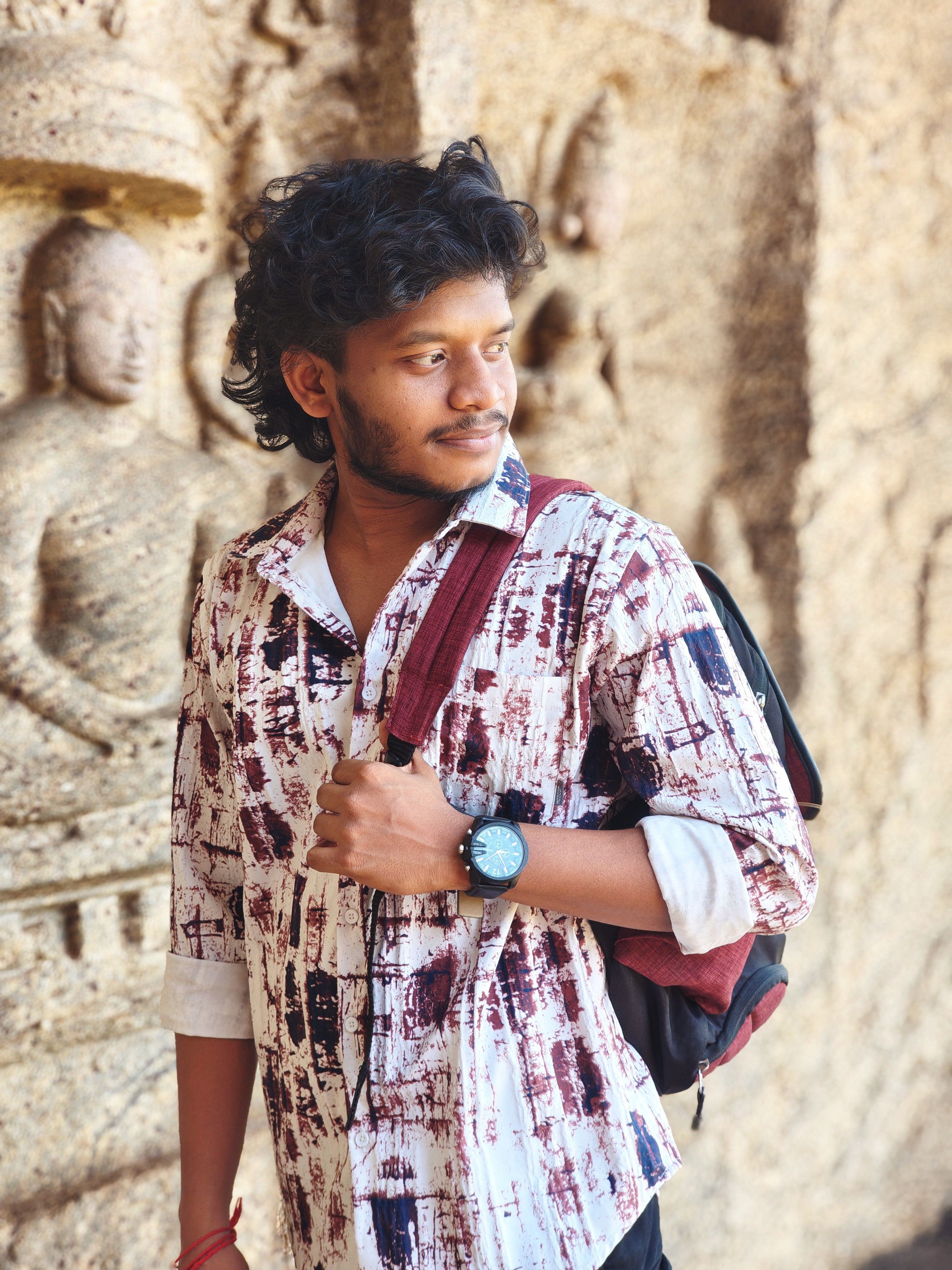 A young man stands near ancient stone carvings in a historic temple.
