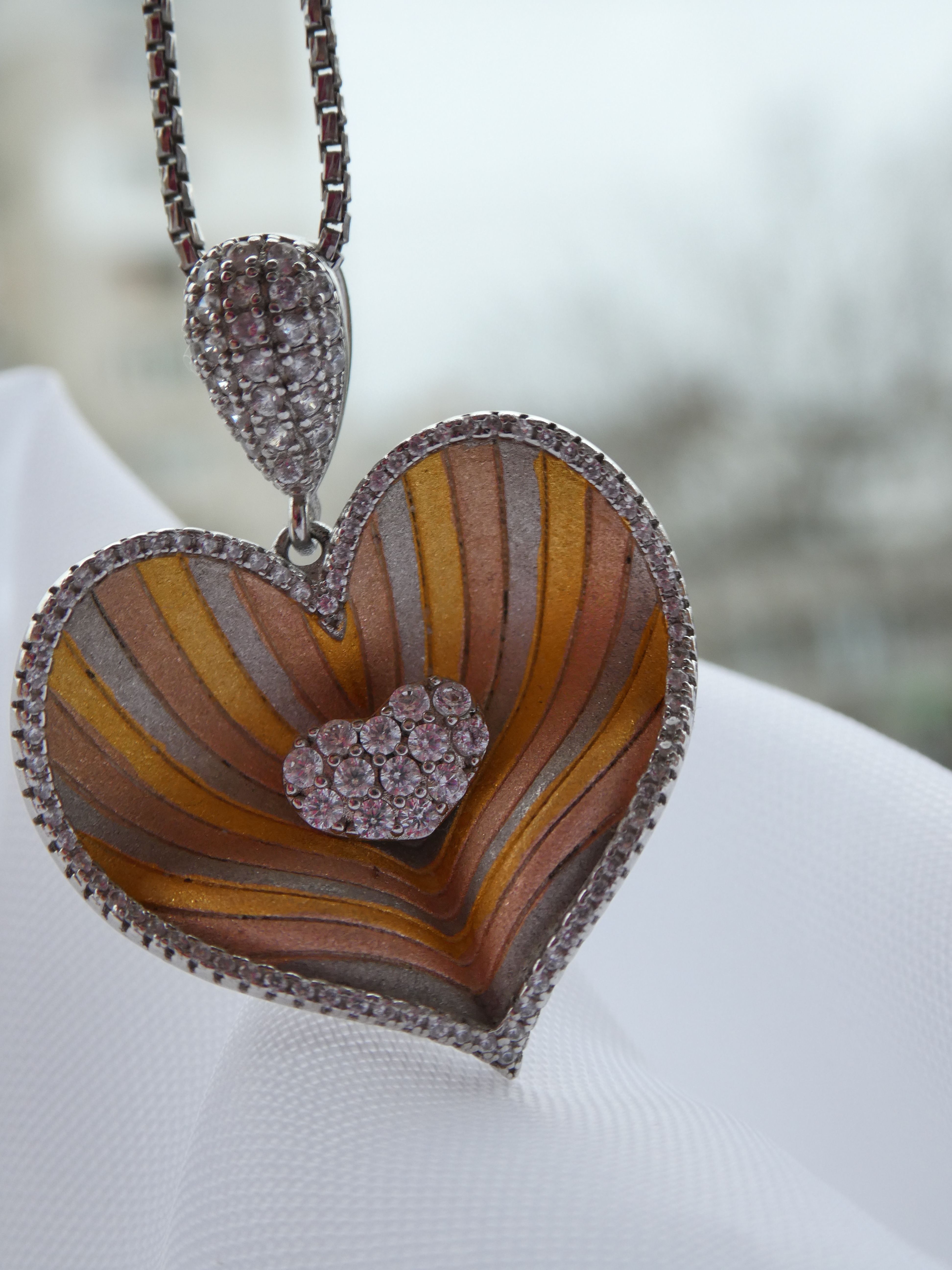 Close-up of a heart-shaped pendant encrusted with gemstones, showcasing intricate design.