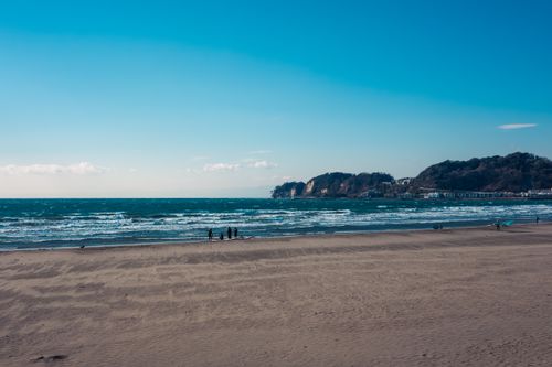 Free Tranquil beach scene with expansive ocean and distant hills under a clear blue sky. Stock Photo