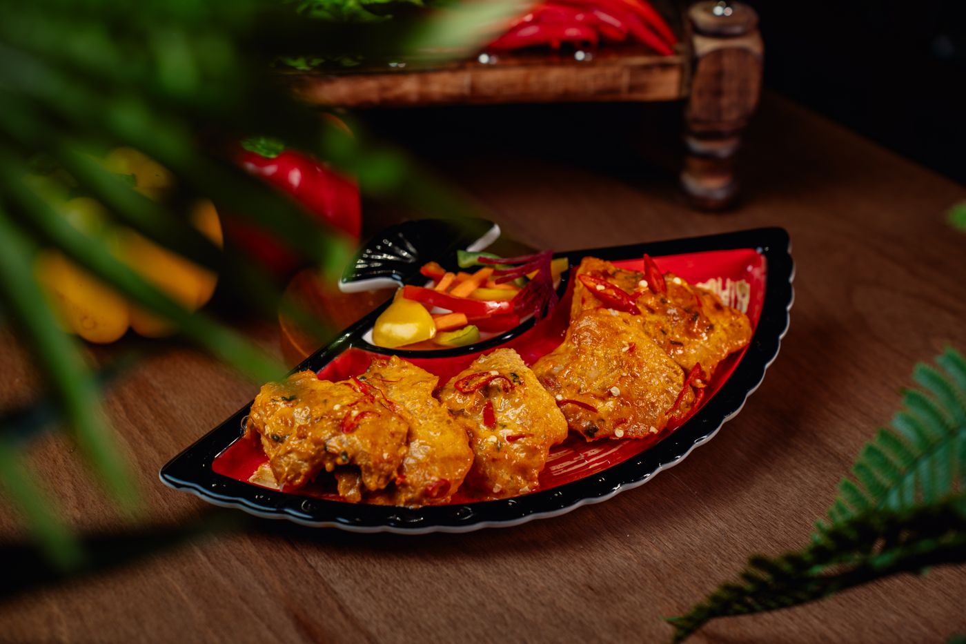 Delicious spicy grilled chicken served with fresh vegetables on a stylish red and black plate.