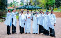 Seven men in traditional attire holding umbrellas outdoors, showcasing cultural heritage.