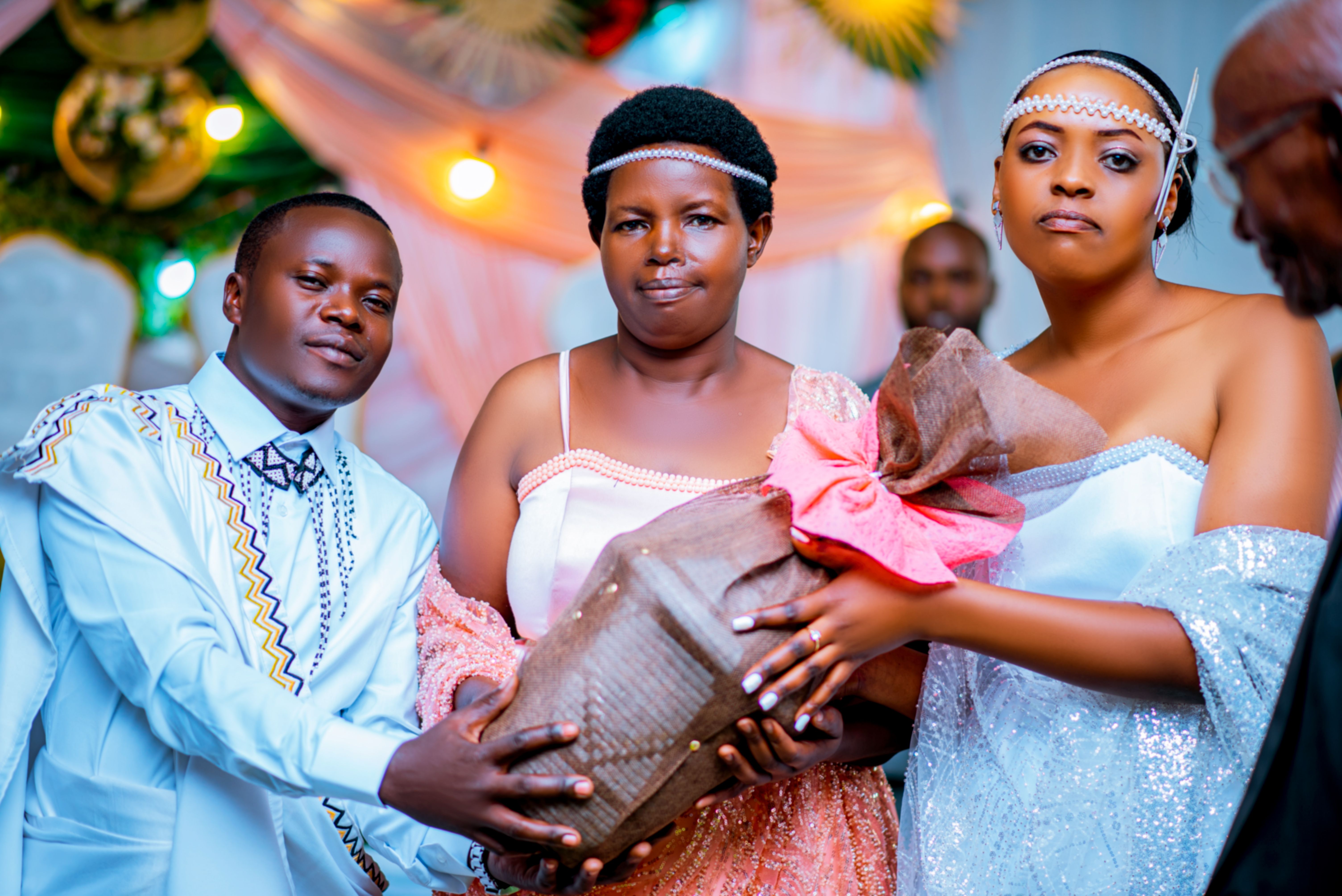 Three adults holding a gift at a colorful celebration. Indoor, festive atmosphere.