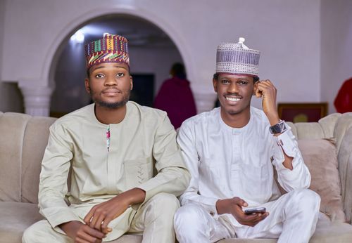 Free Two men in traditional Nigerian clothing sitting on a sofa, smiling warmly indoors. Stock Photo
